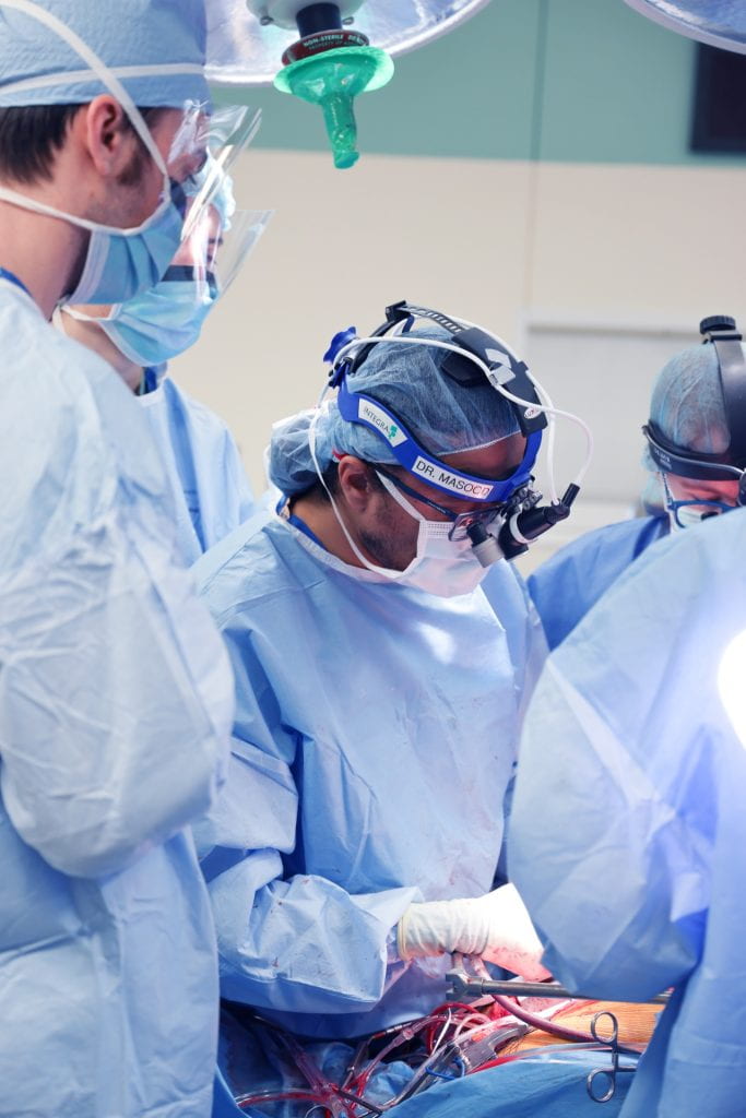 Cardiac surgeon in operating room with surgical staff.